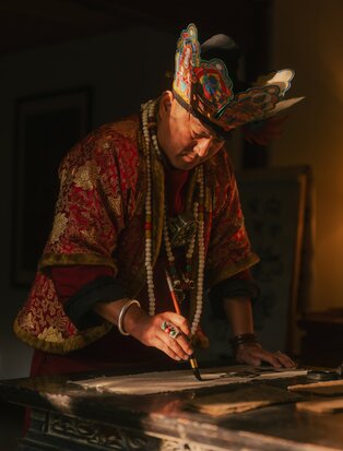 Master craftsperson practising traditional Dongba calligraphy at Amandayan in China.