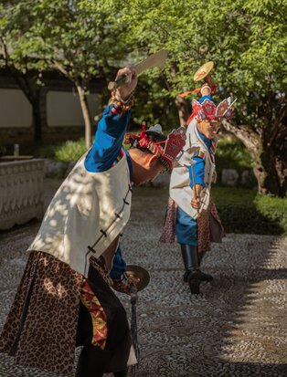 Traditional Naxi cultural performance at Amandayan, with dancer in vibrant costume mid-movement.