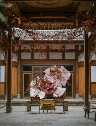 Amanyangyun courtyard with traditional wooden architecture framing a large floral installation during celebrations in China.
