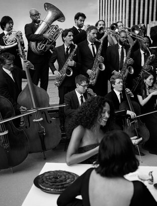 Festive gathering with musicians and guests at Aman New York, black and white photograph.