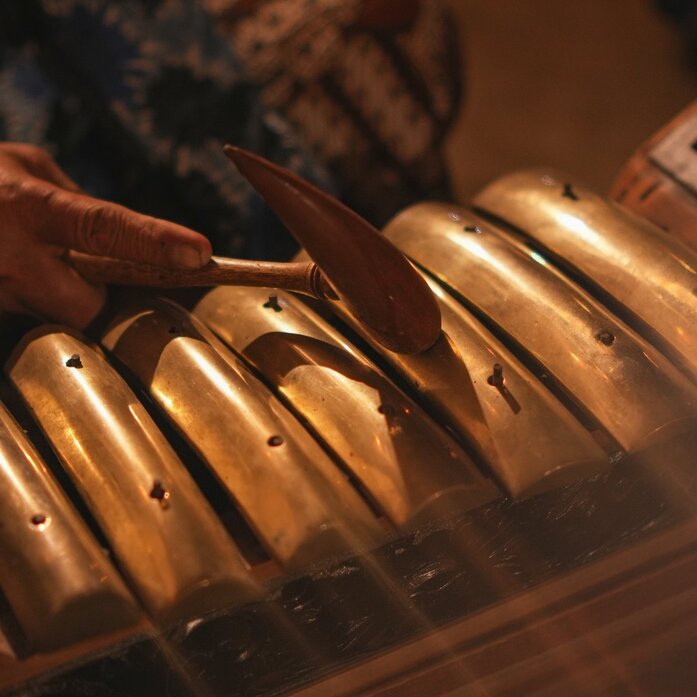 Wayang puppet figures illuminated by warm light at Amanjiwo resort's Javanese dinner experience.