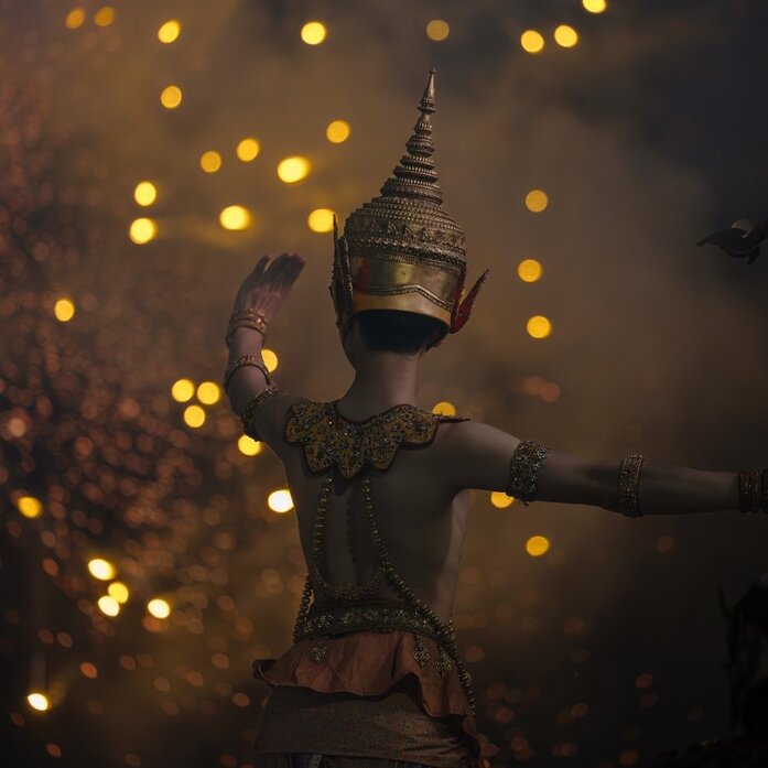 Thai classical dancer in traditional costume performing at Amanpuri, with warm golden lights in the background.