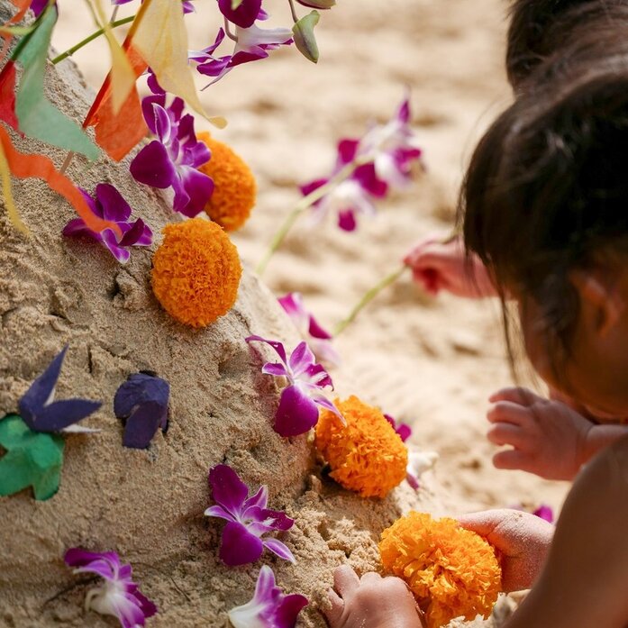 Child arranging colourful flowers during Songkran celebration at Amanpuri, Thailand.