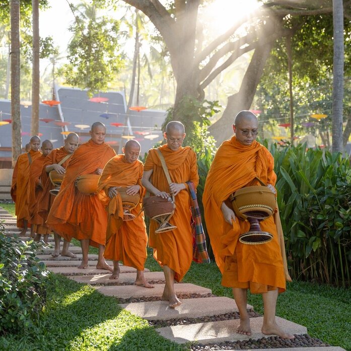 Buddhist monks in saffron robes walk through Amanpuri's gardens during Songkran celebrations.
