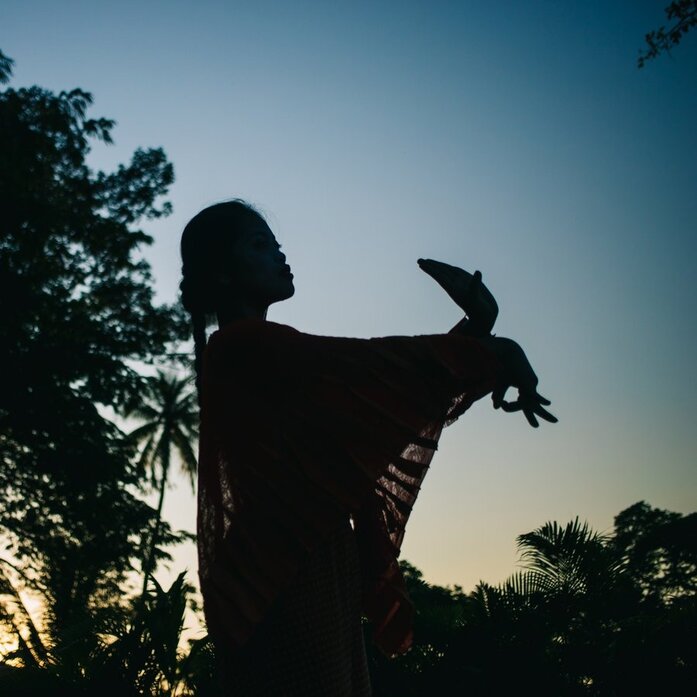 Silhouette of a figure holding a rabbit at Amansara, Cambodia, at dusk.