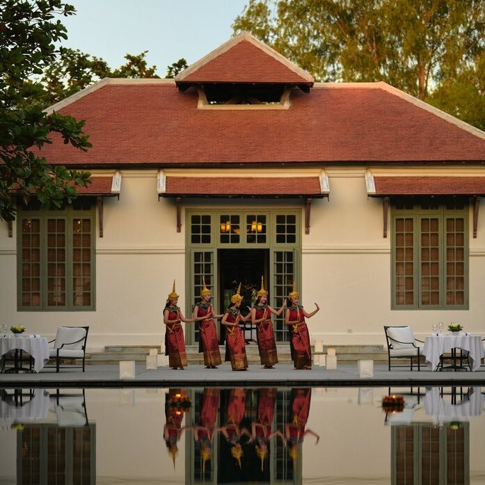 Dancers in traditional Lao dress perform by the pool at Amantaka during an evening celebration.