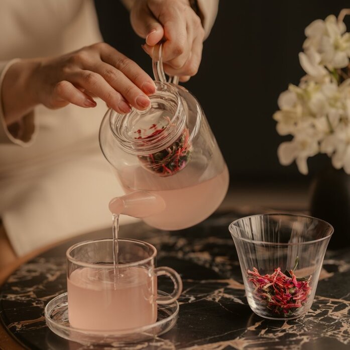 At Aman Nai Lert Bangkok, pink tea is poured from a glass teapot into a delicate cup.