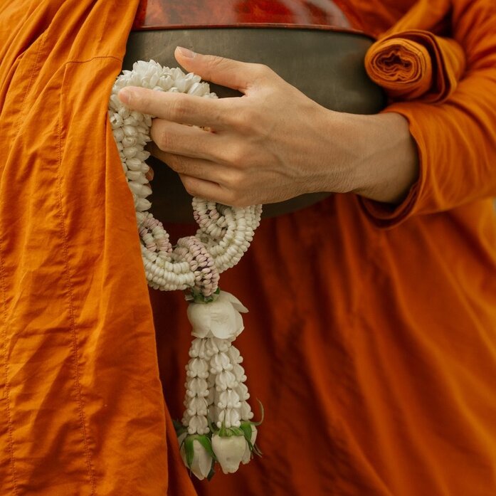 Monk holding white prayer beads and sacred text at Aman Nai Lert Bangkok, Thailand.