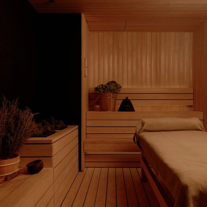 Wooden sauna interior at Aman Nai Lert Bangkok with bench seating and warm lighting.