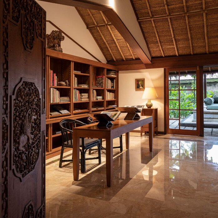 The Library at Amandari, a wood-panelled reading room with carved doors and shelving in Bali.