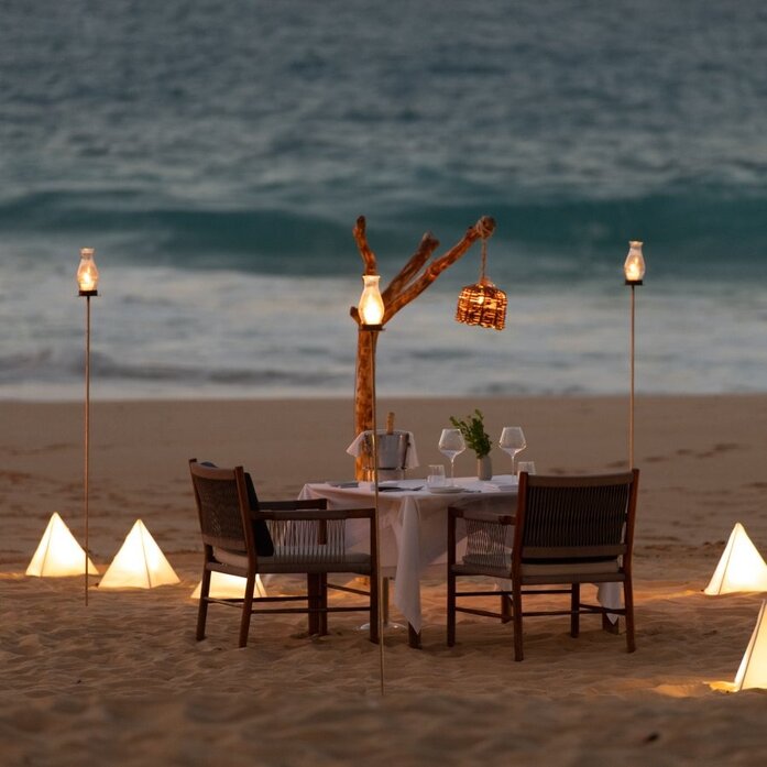 Dîner privé sur la plage à Amanera, en République dominicaine, avec table dressée et lanternes.