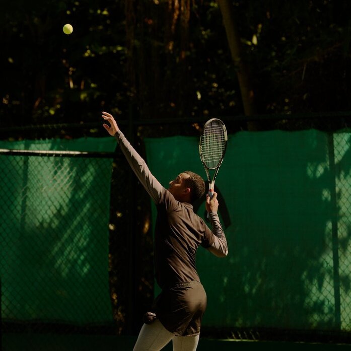 Joueur de tennis en action sur un court illuminé à Amanera, resort en République dominicaine.