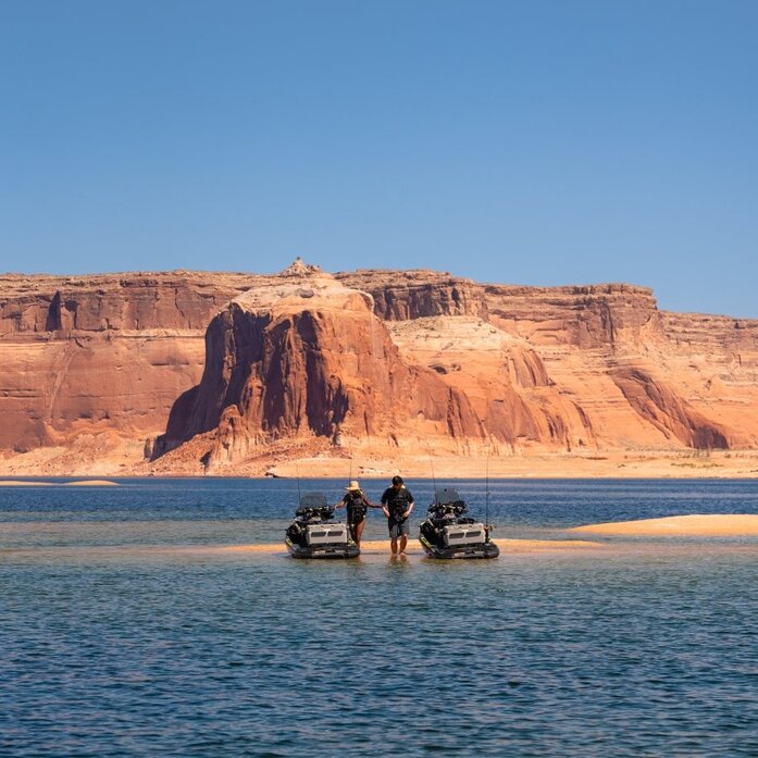 Small boat with passengers on Lake Powell, with red rock formations of Amangiri's desert landscape in the background.