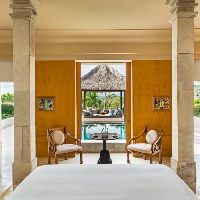 Garden Suite principal bedroom at Amanjiwo, Indonesia, with view of pool pavilion through open doors.