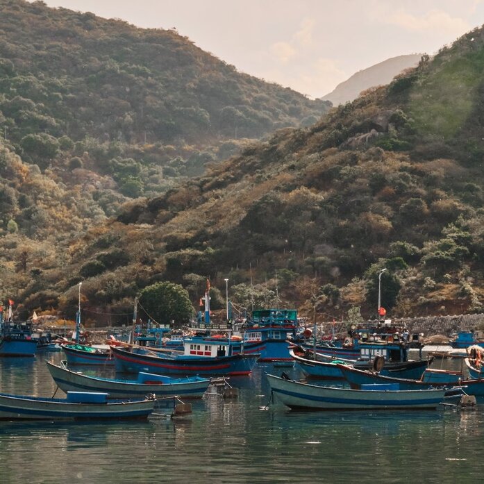 Moored fishing boats in Vinh Hy Bay at Amanoi, Vietnam, surrounded by forested hillsides.
