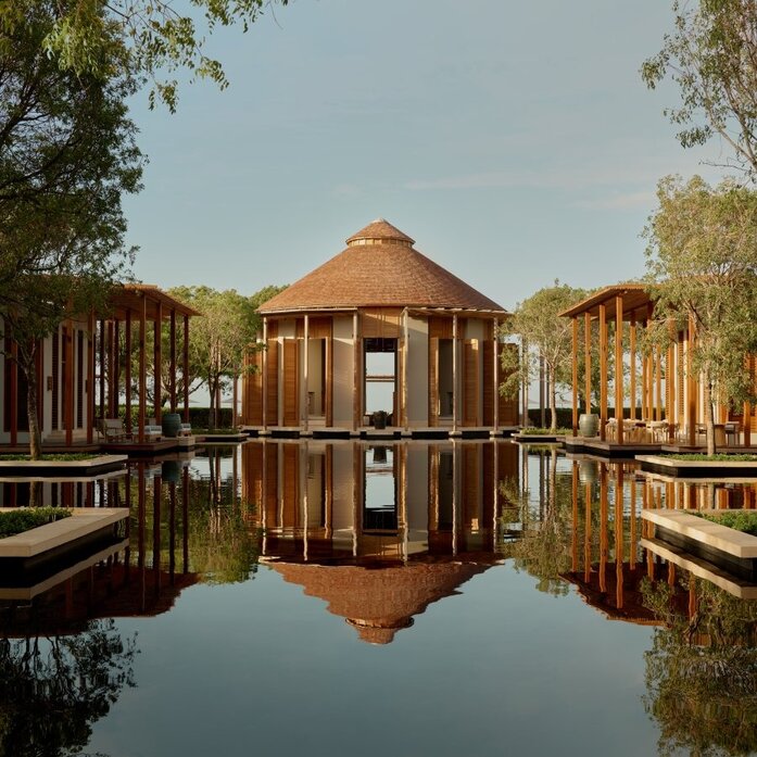 Amanyara's octagonal pavilion reflected in still water, framed by native trees and wooden walkways.