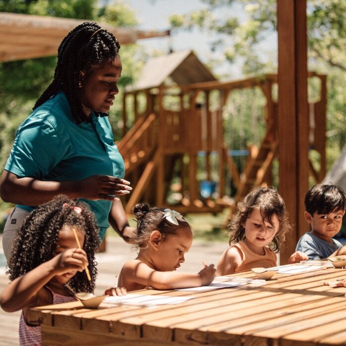 Educator at Amanyara's Nature Discovery Centre leads children through a hands-on learning activity outdoors.