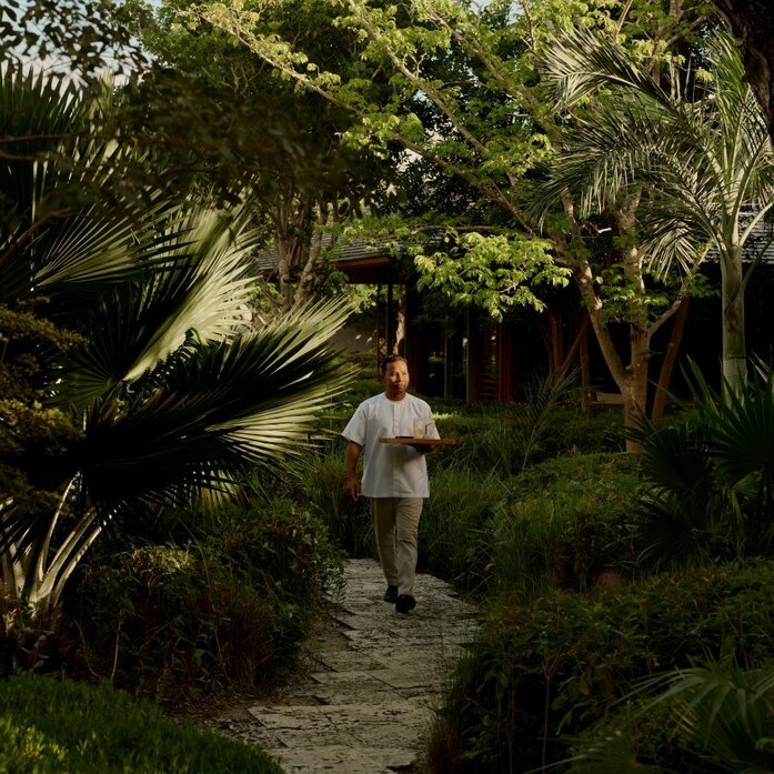 Staff member walking along a lush garden pathway at Amanyara, Turks and Caicos.