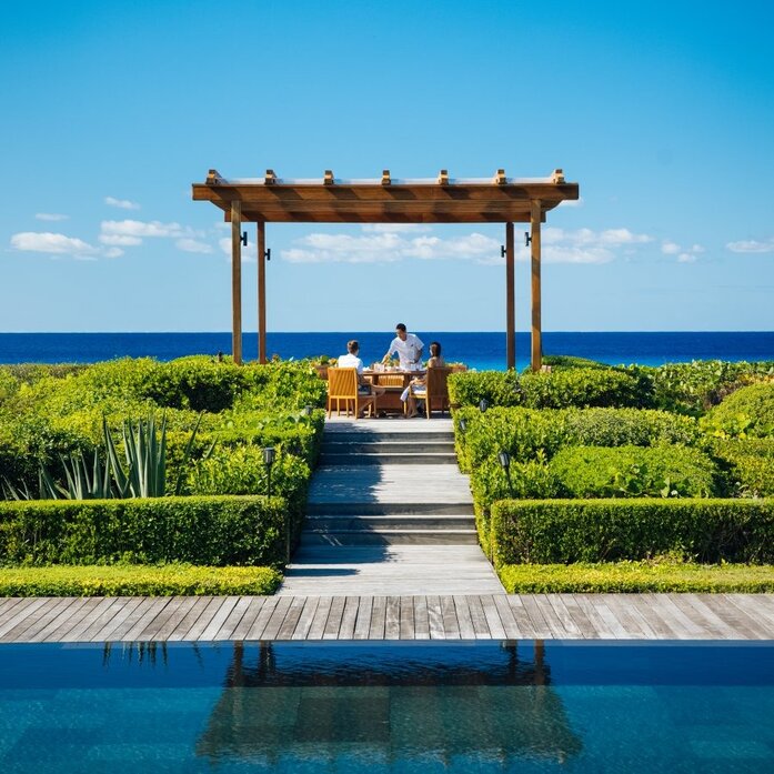 Wooden pergola and reflecting pool at Amanyara's beachfront Beach Sala Villa, overlooking turquoise waters.