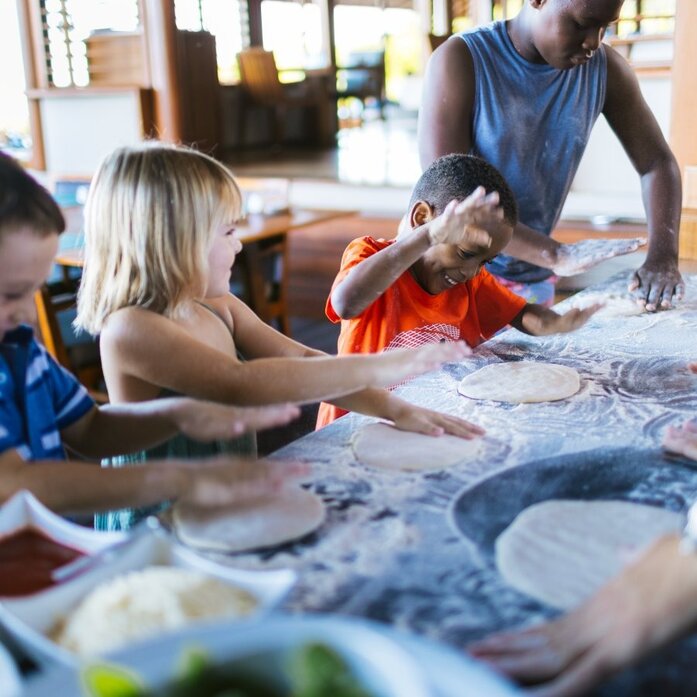 Children and an adult preparing pizza together at Amanyara.