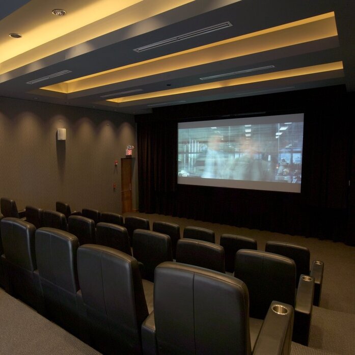 Screening room at Amanyara with tiered seating and projection screen, warm ceiling lighting.