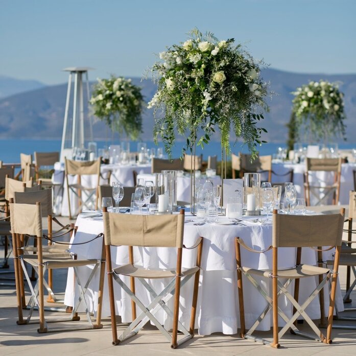 Outdoor dining table set for celebration at Amanzoe with sea views and floral centrepieces.