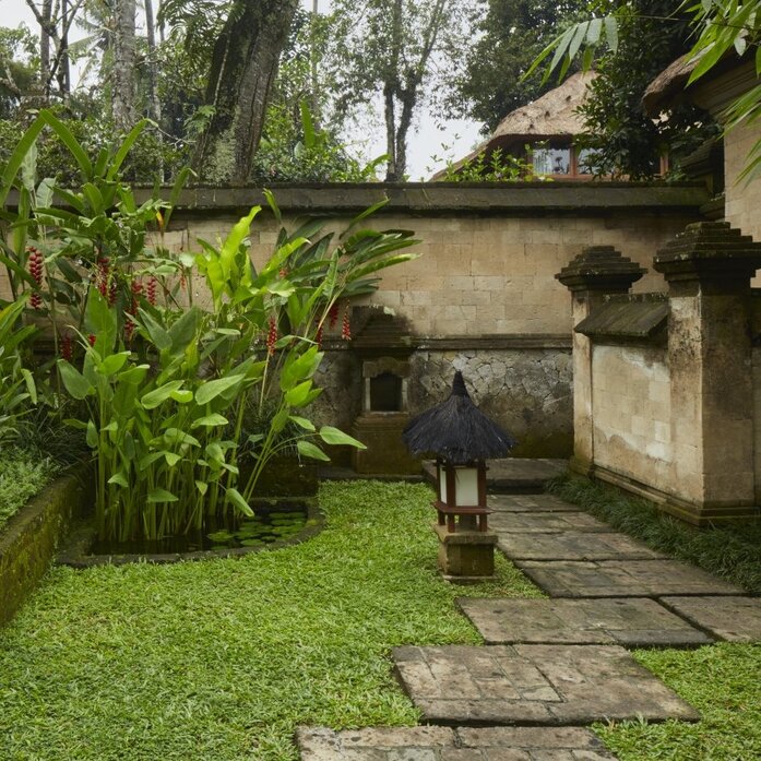 Amandari resort Valley Suite garden with stone pathway, lush tropical plants, and traditional stone structure.