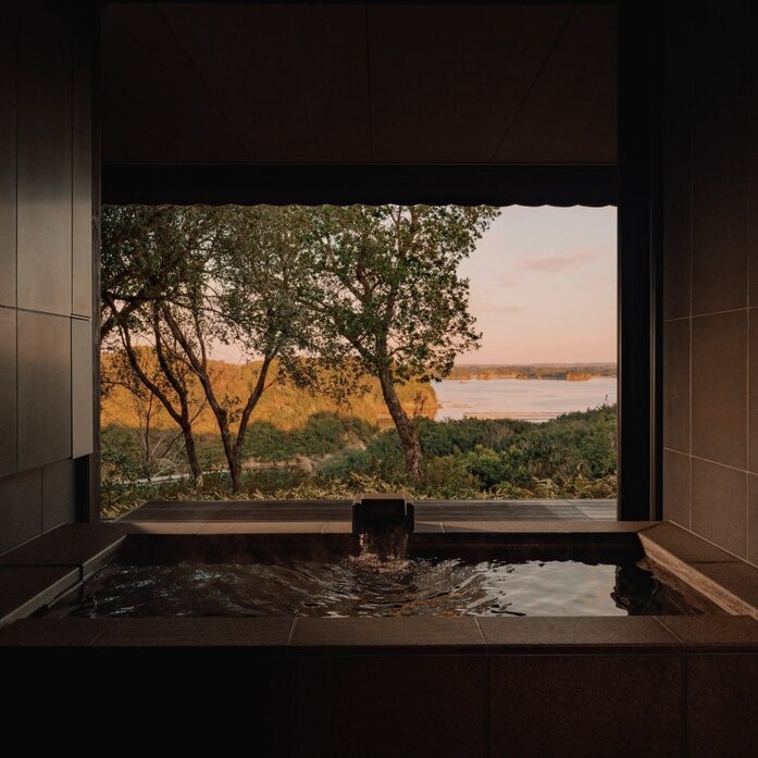 Private onsen at Amanemu with view of Japanese countryside at sunset.