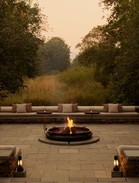 Fire pit seating area at Aman-i-Khas, India, at dusk with stone benches arranged in a circle.