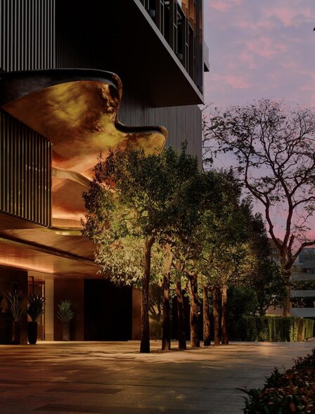 Aman Nai Lert Bangkok exterior illuminated at dusk, with warm lighting accentuating the building's architecture and surrounding tropical gardens.