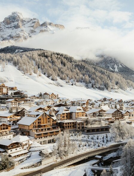 Snow-covered Alpine village with wooden chalets nestled at the base of mountains at Aman Rosa Alpina.