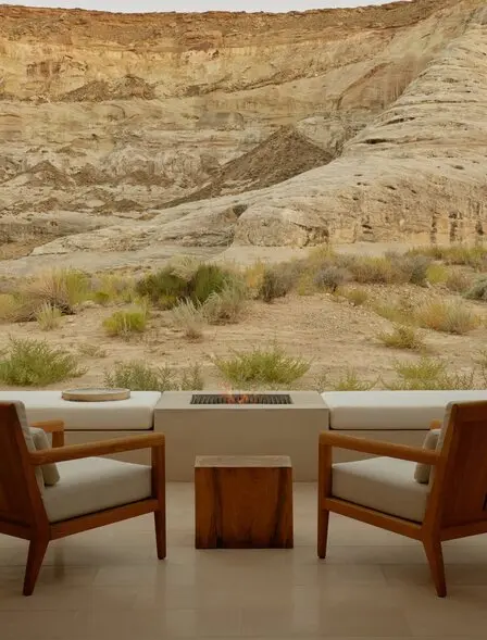 Back patio at Amangiri with two burgundy chairs, wooden table, and desert landscape photograph.