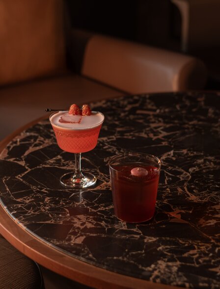 アマン ナイラート バンコクのラウンジで、黒い大理石のテーブルに置かれたカクテルとスピリッツのグラス。