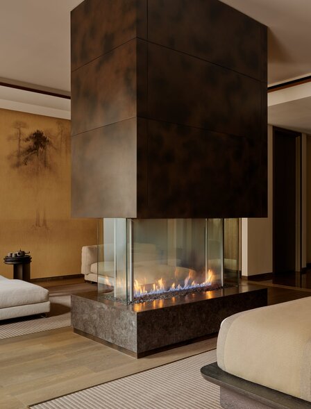 Grand Suite at Aman New York with fireplace, minimalist furnishings, and warm wood tones.