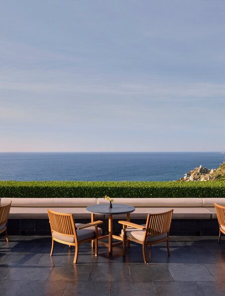 Wooden chairs and table on a terrace overlooking the sea at Amanoi, Vietnam.