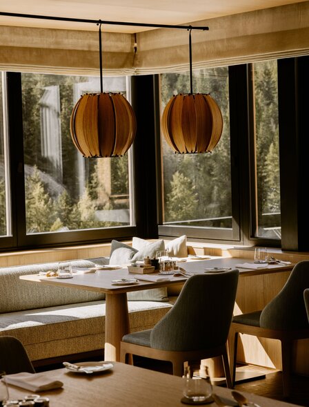 Dining room at Aman Rosa Alpina with wooden table, pendant lights, and framed artwork on walls.