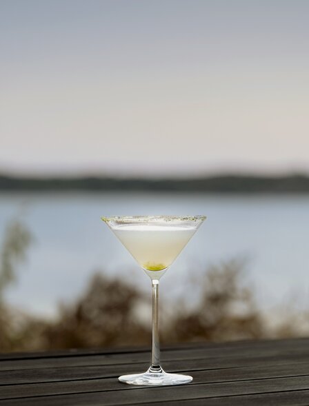 Cocktail glass at Amanemu resort bar overlooking calm water at dusk.