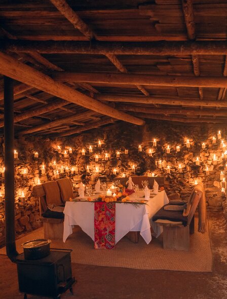 Candlelit potato shed at Amankora with warm string lights and traditional Bhutanese textiles draped overhead.