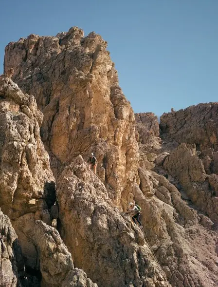 Rugged mountain cliffs under clear blue sky at Aman Rosa Alpina resort, Italy.