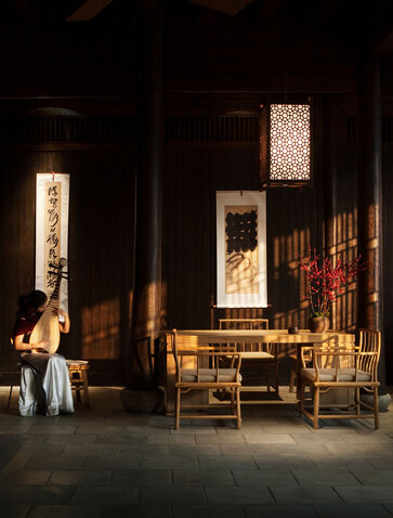 Portrait of Aman Fayun at Amanyangyun, evening interior with warm lighting and traditional wooden furnishings.