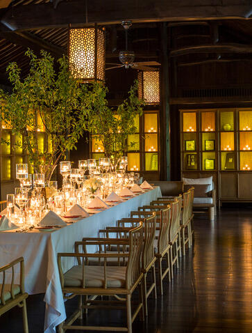 Candlelit dining table at Amanfayun, a traditional Chinese village, with lanterns glowing overhead and wooden architecture in the background.
