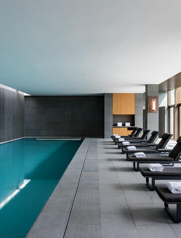 Indoor swimming pool at Amanyangyun with loungers and minimalist architecture.
