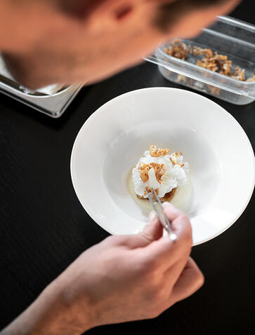 Hand holding white plate with delicate appetiser at Amanyangyun.