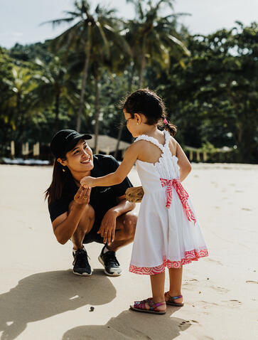 Famille sur la plage de sable blanc à Amanpuri, resort en Thaïlande.