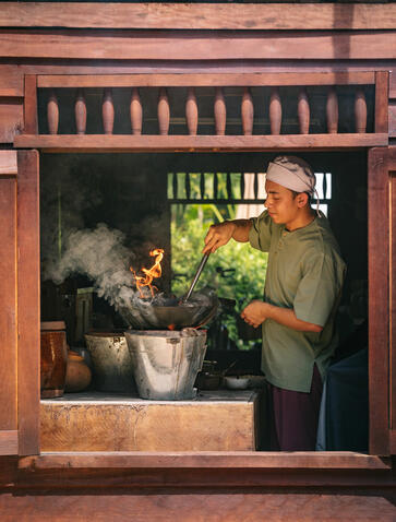 Staff member arranging fresh flowers at Amansara's wooden window display.