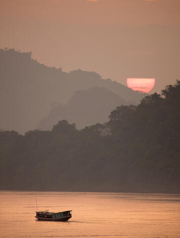 Wooden boat on the Mekong River at sunset, Amantaka, Laos.