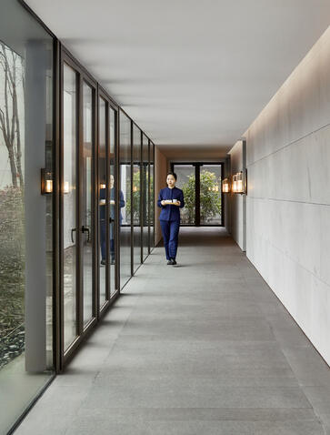 Corridor with floor-to-ceiling glass partitions at Amanyangyun residence, looking towards entrance pavilion.