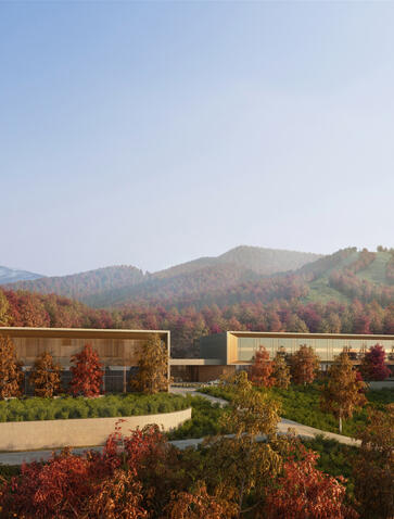 Autumn landscape at Aman Niseko with mountain views and terracotta-coloured structures among foliage.