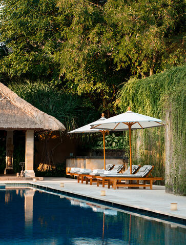Swimming pool at Aman Villas at Nusa Dua with thatched pavilion and white parasol.