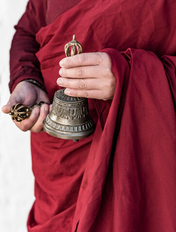 Monk in maroon robes holding a dorji and drilbu during a blessing ceremony at Amankora, Bhutan.